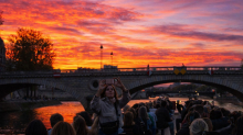 Passagers sur un bateau de croisière sur la Seine admirant un coucher de soleil spectaculaire à Paris sous un pont