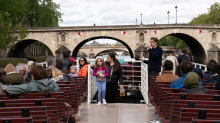 Pasajeros sentados en un barco de crucero por el Sena en París pasando bajo un puente durante una visita guiada.
