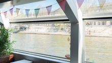 Vista del río Sena desde el interior de un barco de crucero en París decorado con banderines de colores.