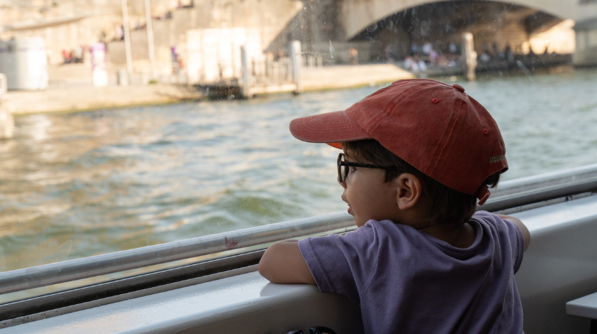 Enfant regardant la Seine depuis un bateau-mouche lors d’une croisière touristique à Paris