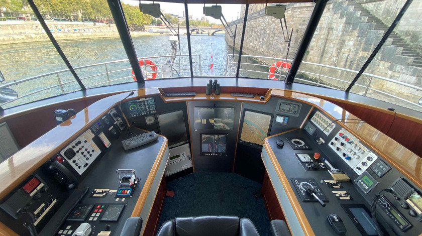 Wheelhouse of the Lutécia boat with navigation screens and control panels, view of the Seine and a Parisian bridge, during European Heritage Days