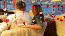 Pareja abrazada vista a través de decoraciones de corazones en un barco